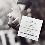 Matching Morse code couple bracelets on personalized card — 18k gold and oxidized silver set, styled on black-and-white photo of holding hands